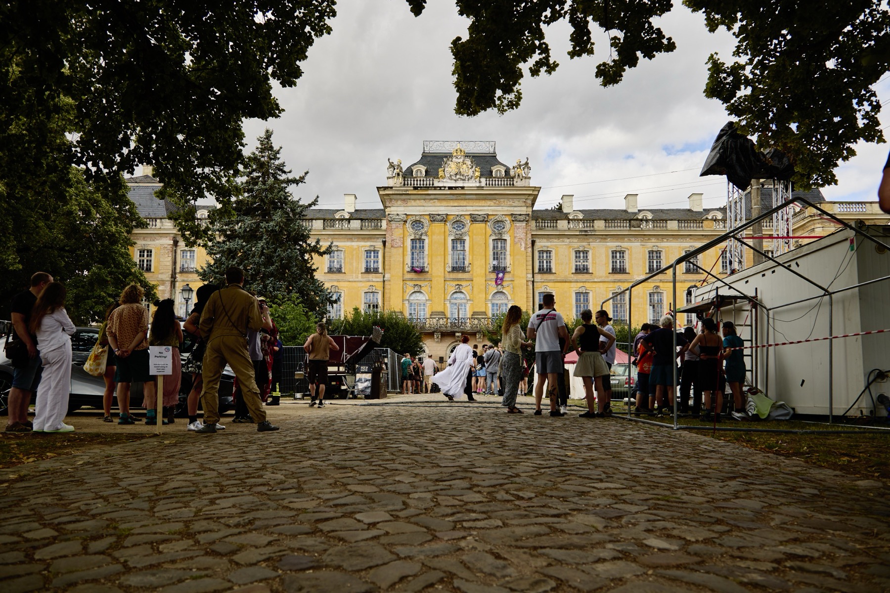 Schloss Dornburg von vorn: Menschen stehen auf dem Pflaster vor der gelben Fassade.