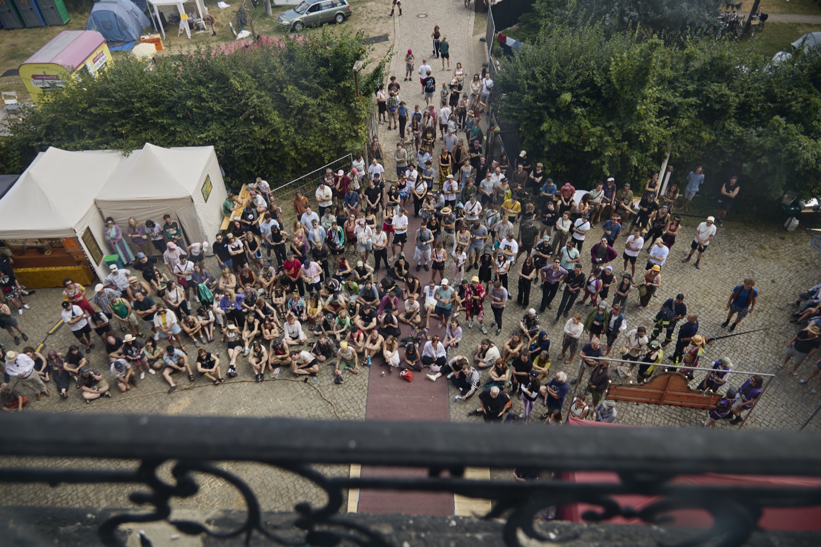 Blick von oben auf den vollen Ehrenhof: Hunderte Menschen sitzen und stehen vor einer Bühne.